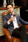 Um jovem com um copo de vinho tinto — Fotografia de Stock