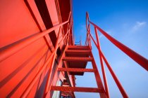 Visão de baixo ângulo de guindaste pórtico industrial vermelho contra o céu azul — Fotografia de Stock