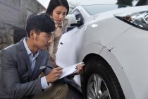 Young man checking car damage with young woman — Stock Photo