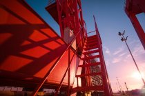 Vue à angle bas de la grue portique industrielle rouge au lever du soleil — Photo de stock
