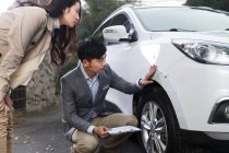 Jeune homme vérifiant les dommages de voiture avec la jeune femme — Photo de stock