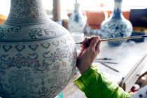 Abgeschnittene Aufnahme einer Person mit Pinsel und schönem asiatischen Porzellan, jingdezhen jiangxi, China — Stockfoto