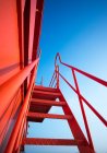 Vue à angle bas de la grue portique industrielle rouge contre le ciel bleu — Photo de stock