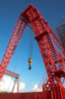 Low angle view of red industrial gantry crane against blue sky — Stock Photo