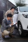 Jovem verificando danos no carro com a jovem mulher — Fotografia de Stock