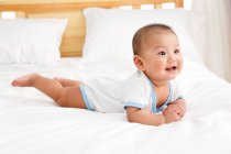 Adorabile felice cinese bambino sdraiato sul letto — Foto stock