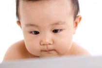 Primer plano vista de lindo asiático bebé niño usando computadora portátil sobre fondo blanco, enfoque selectivo - foto de stock