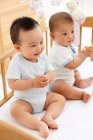 Zwei süße glücklich asiatische Babys sitzen zusammen in Krippe — Stockfoto