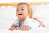 Primo piano vista di adorabile felice cinese bambino sdraiato sul letto — Foto stock
