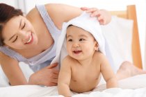 Happy young mother and cute baby with towel on head at home — Stock Photo