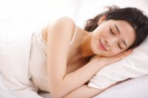 Mujer joven durmiendo en el dormitorio - foto de stock