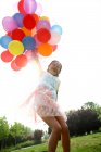 Girl holding bunch of balloons — Stock Photo