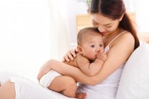 Glücklich junge asiatische Mutter hält entzückendes kleines Baby zu Hause — Stockfoto