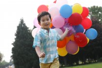 Menino segurando monte de balões — Fotografia de Stock