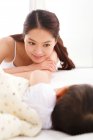 Happy young mother looking at adorable baby sleeping on bed — Stock Photo