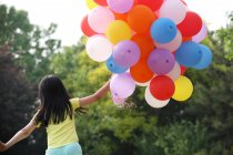 Chica sosteniendo montón de globos - foto de stock