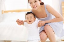 Happy young mother with cute baby smiling at camera — Stock Photo