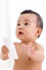 Süße asiatische Baby Junge hält Smartphone und schaut nach oben — Stockfoto