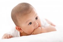 Adorable chino bebé niño acostado en la cama - foto de stock