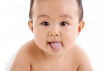 Adorable asiatique bébé garçon montrant la langue dehors et regardant caméra sur fond blanc — Photo de stock