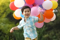 Boy holding bunch of balloons — Stock Photo