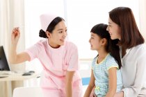 The female nurse is giving the little girl the temperature. — Stock Photo