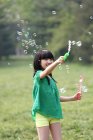 Дівчина робить мильні бульбашки на відкритому повітрі — стокове фото