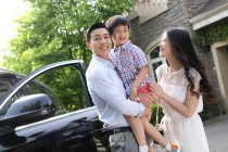 Happy family standing next to the car — Stock Photo