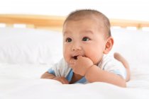 Primer plano vista de adorable asiático bebé niño acostado en la cama - foto de stock