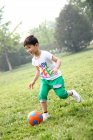 Мальчик играет в футбол в поле — стоковое фото