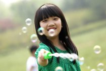 Дівчина робить мильні бульбашки на відкритому повітрі — стокове фото