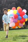 Boy holding bunch of balloons — Stock Photo
