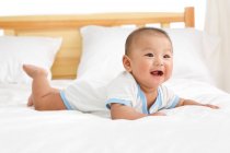 Carino felice asiatico bambino sdraiato su letto — Foto stock