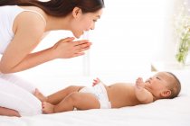 Happy young asian mother playing with adorable little baby at home — Stock Photo
