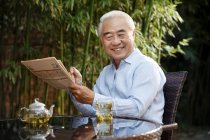 Uomo anziano seduto in cortile a bere tè — Foto stock