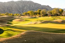 Дивовижний зелений газон на полі для гольфу і красиві гори в сонячний день — стокове фото