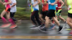 Низкая часть людей, бегущих через марафонскую гонку, размытое движение — стоковое фото