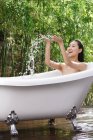 Красива усміхнена молода азіатка купається у ванній на відкритому повітрі — стокове фото