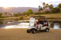 Dos hombres conduciendo un carrito de golf - foto de stock