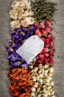 Dried flowers and tea leaves with tea package, top view — Stock Photo