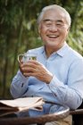 Älterer Mann sitzt im Hof und trinkt Tee — Stockfoto