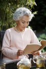 Senior woman reading in yard — Stock Photo