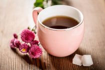 Крупним планом вид на здоровий органічний трав'яний чай, рожеві квіти і цукор на дерев'яному столі — стокове фото
