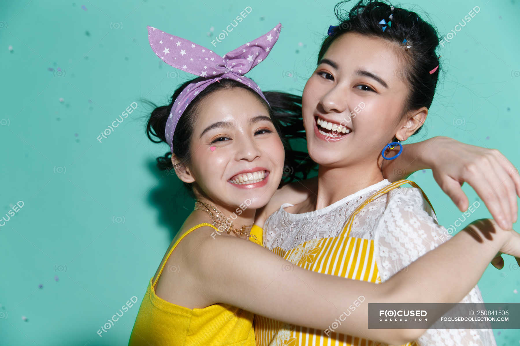 Beautiful Happy Asian Girlfriends Hugging And Smiling At Camera On Blue