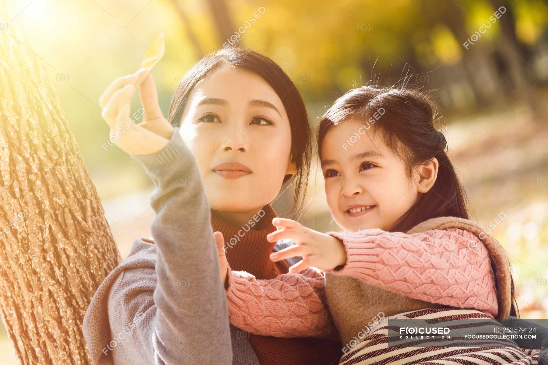 Happy Asian Mother And Daughter Looking At Autumn Leaf In Park