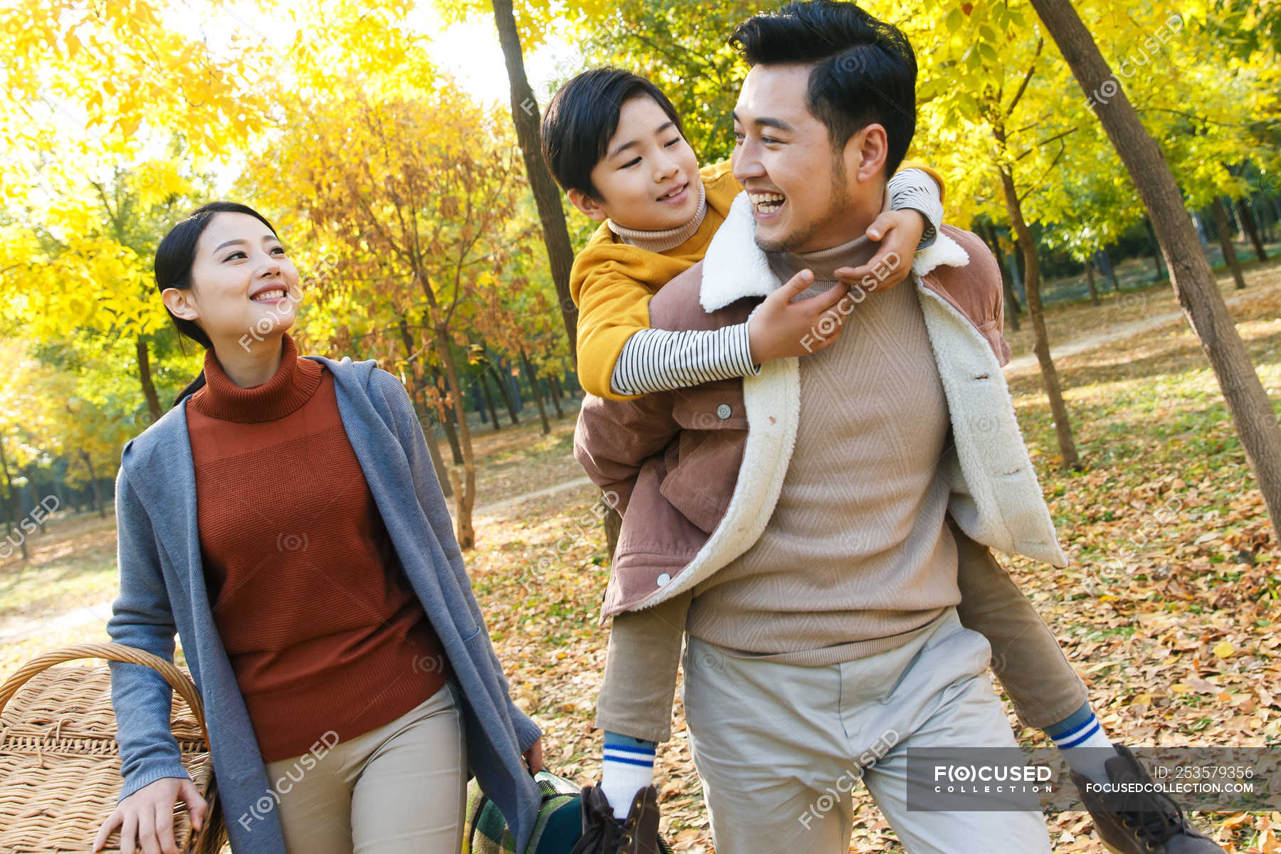 happy-asian-father-giving-piggyback-to-son-in-autumnal-park-boy