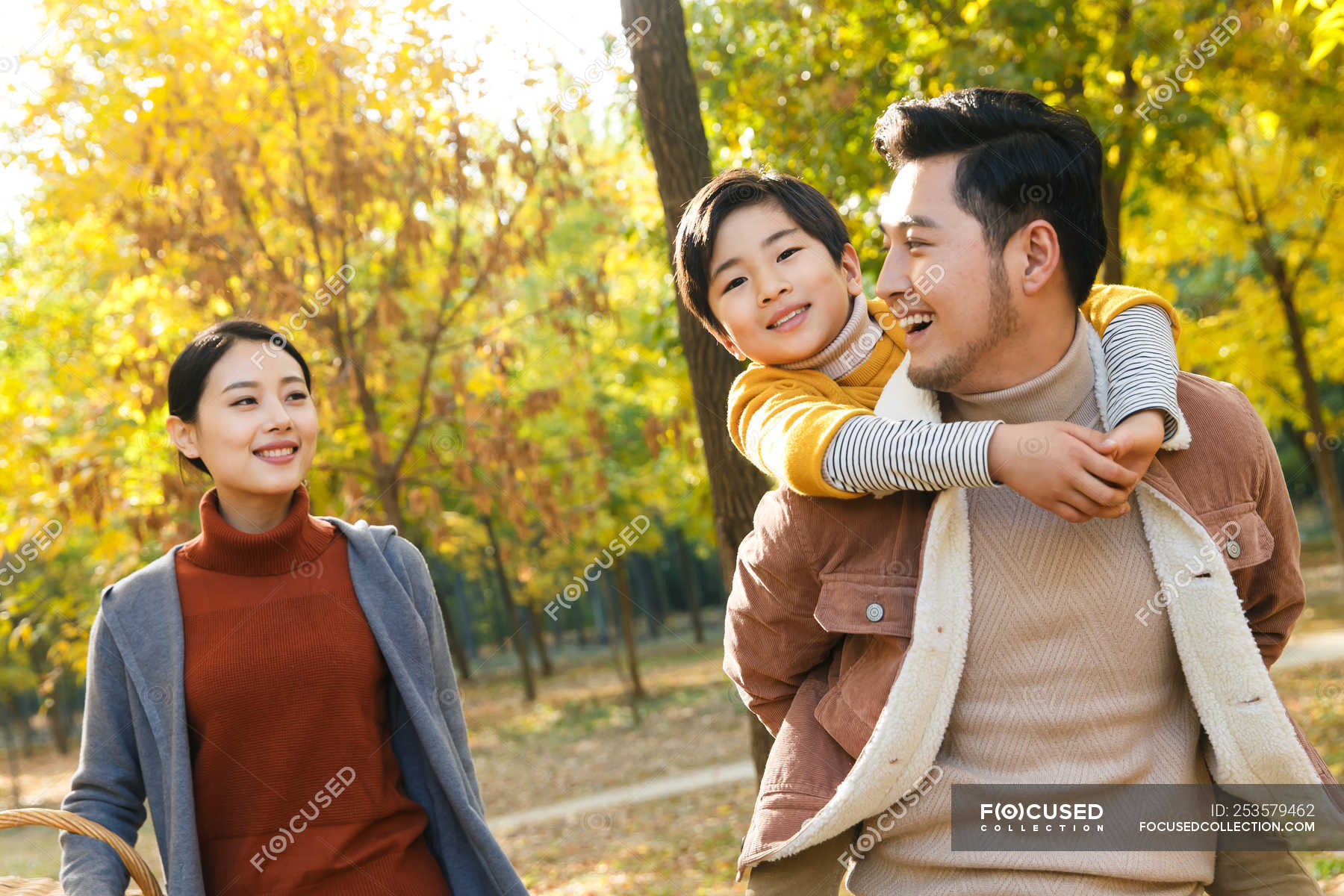 happy-asian-father-giving-piggyback-to-son-in-autumnal-park-together