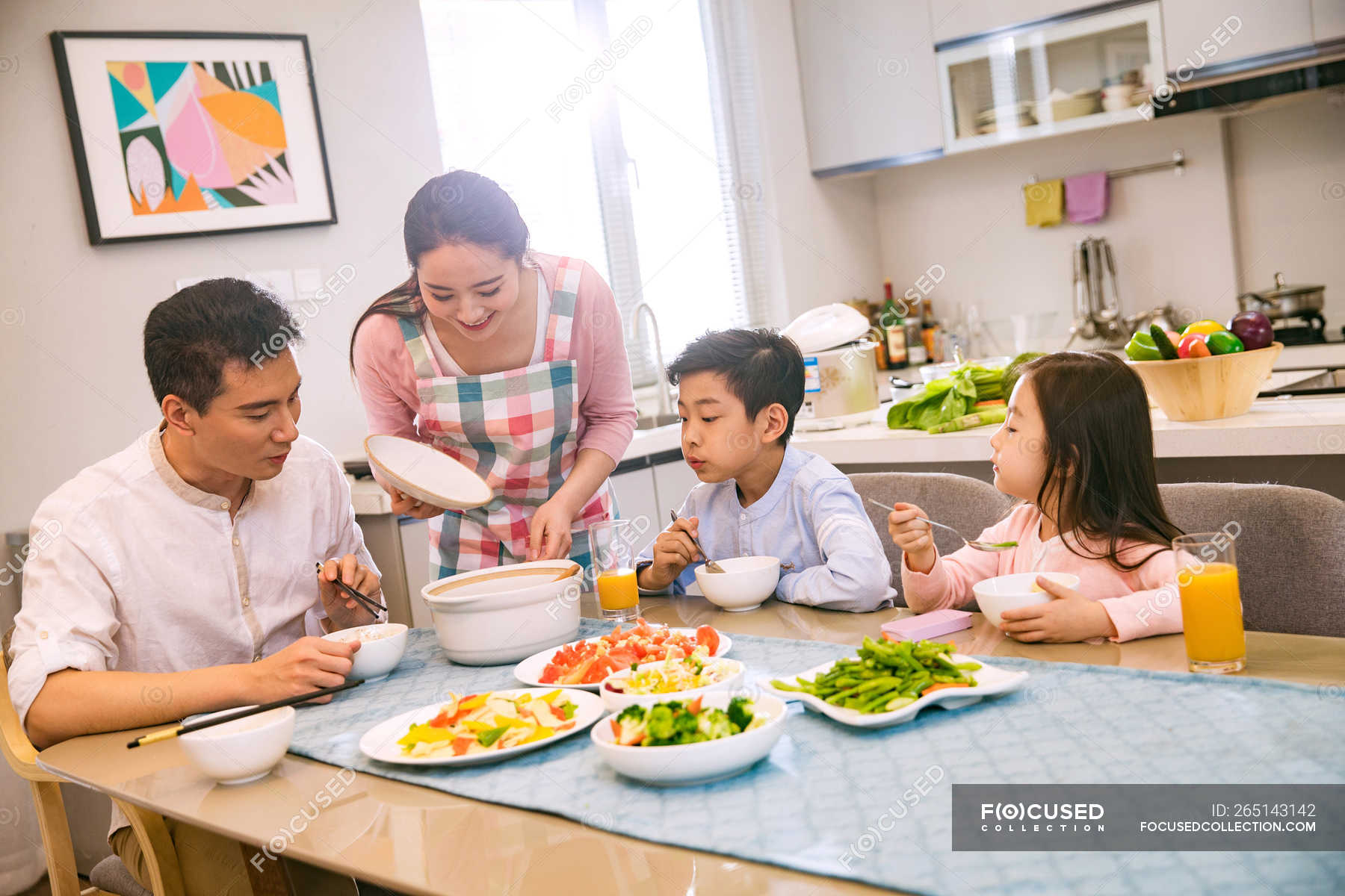 Happy asian family with two kids having dinner together at home ...
