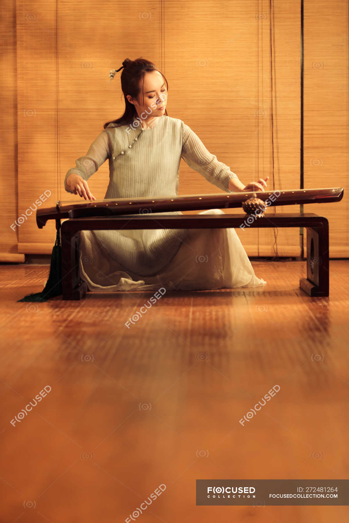 Focused young asian woman playing traditional chinese guzheng ...