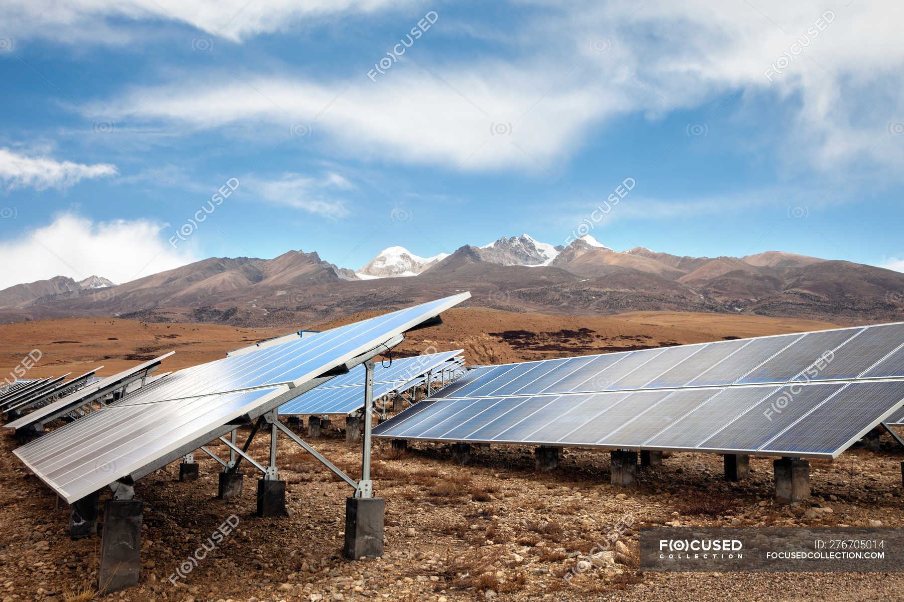 Solar panels in valley and beautiful mountains on horizon — plants